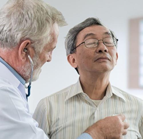A physician listening to the heart of an elderly male patient