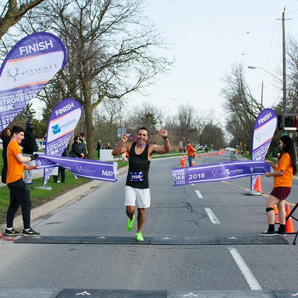 Runner crossing a finish line in first place at the strides for stroke event