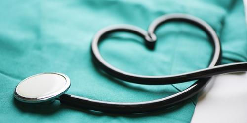 Stethoscope in a heart shape, folded on a set of scrubs