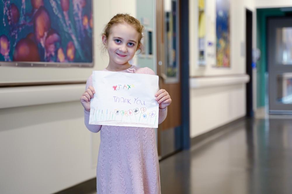 Jax holding a thank you card while in the hallway of a hospital