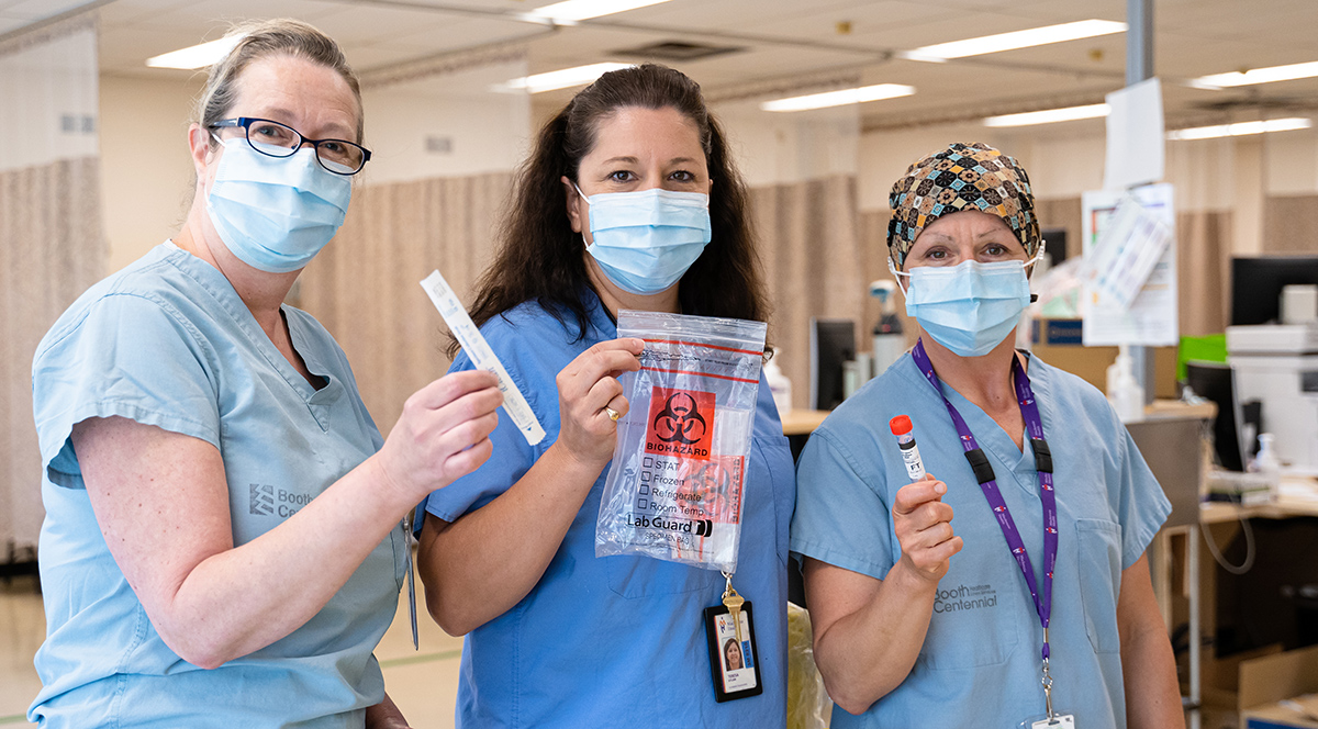 Three nurses in masks holding up assessment tools