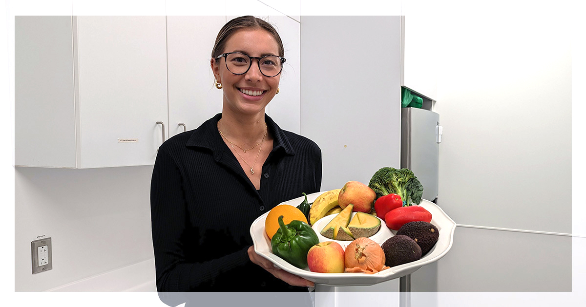 Staff member holding up a plate of fruits and vegetables