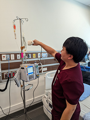An image of a male nurse scanning a barcode on an IV pump