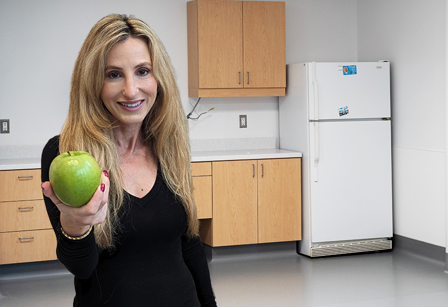Image of Joanna, a dietitian, holding out an apple while standing in a kitchen 