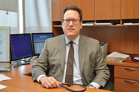 Doctor Bishinsky sitting behind a desk in a suit and tie